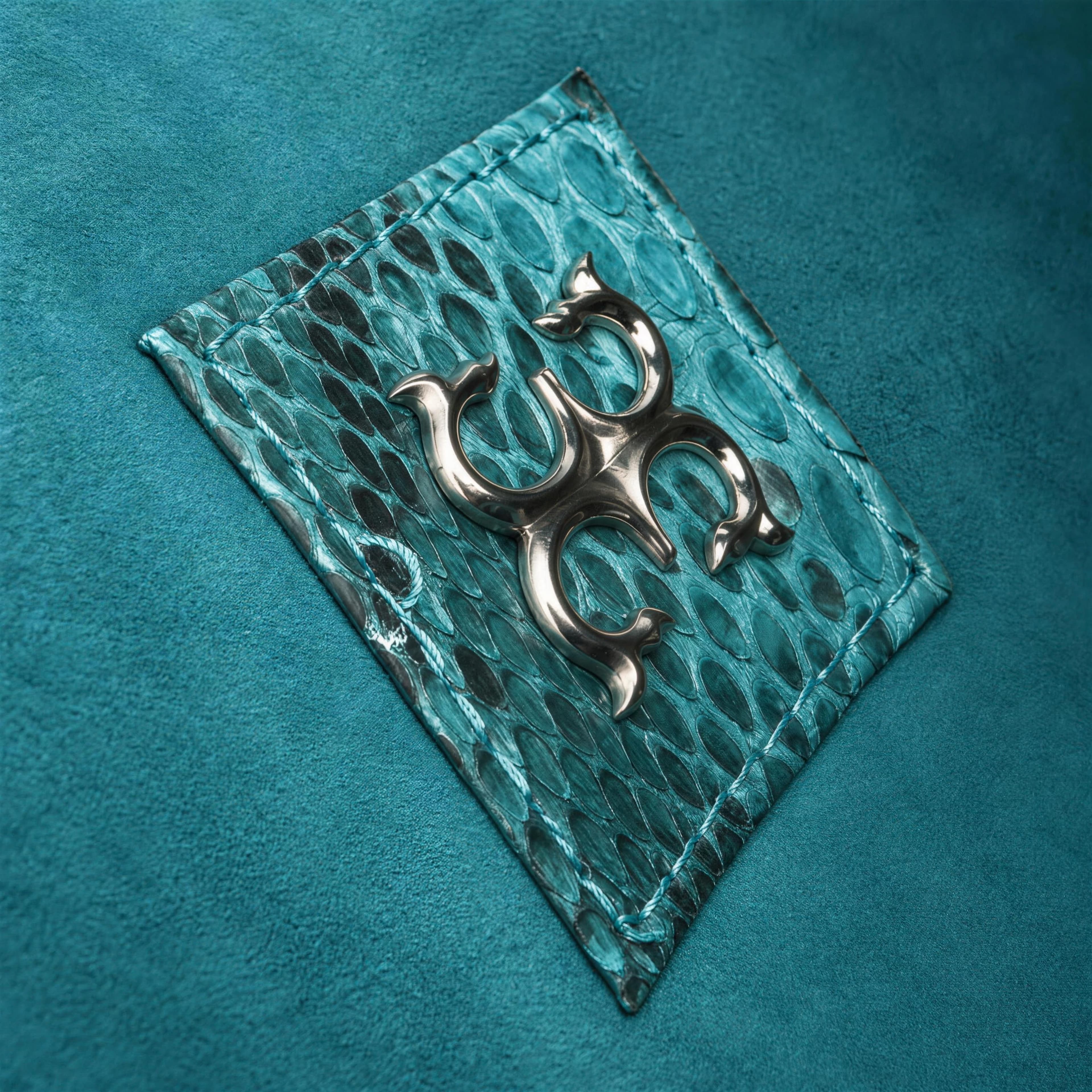 The ALIGATTI seal, a polished metal mark on a patch of python skin inside the bag